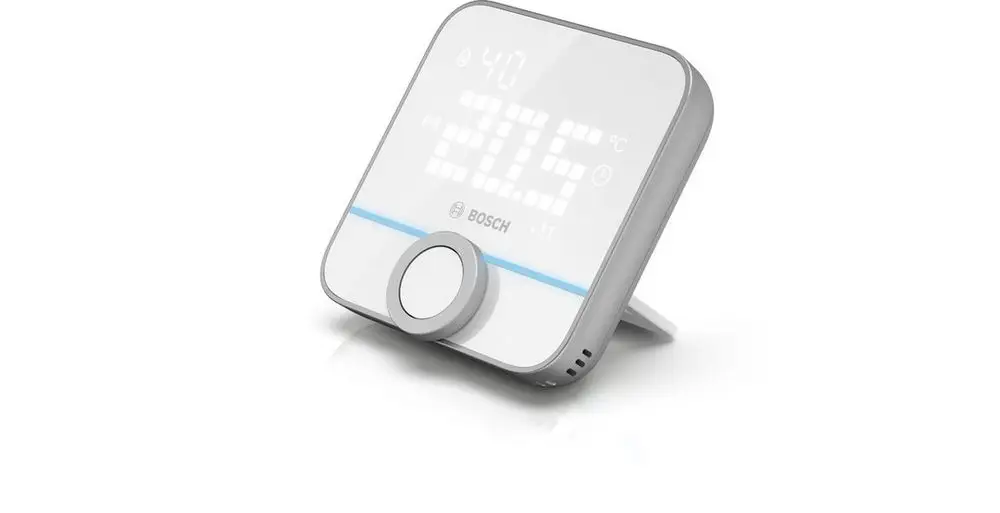 Weißes digitales Thermostat von Bosch mit einem digitalen Display, einem großen Drehknopf und einer stabilen Standfußkonstruktion, abgebildet auf einem neutralen Untergrund.